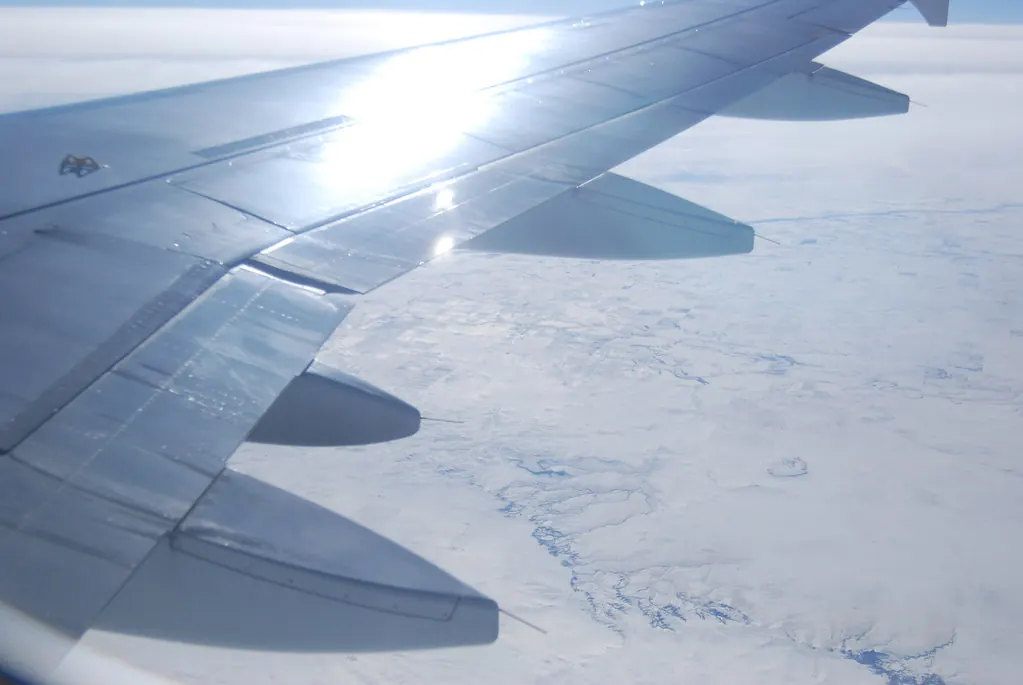 View of an airplane wing over snowy landscape from a window seat