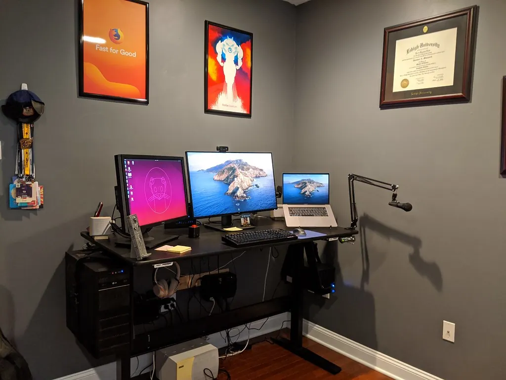 Home office with two monitors, a laptop, webcam and microphone on a standing desk