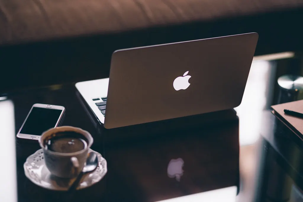 Open laptop on a desk next to a smartphone and a cup of coffee