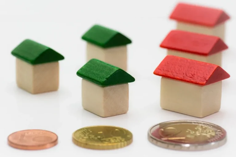 Small toy houses beside stacked coins, representing budgeting and saving