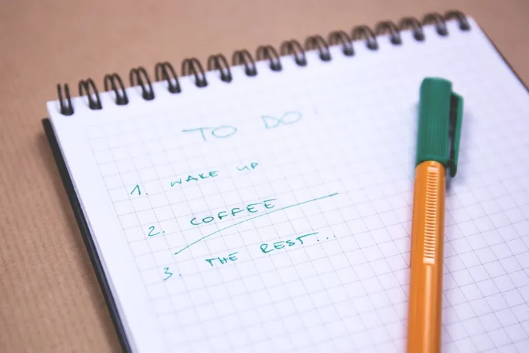 A handwritten to-do list in a notebook with a pen