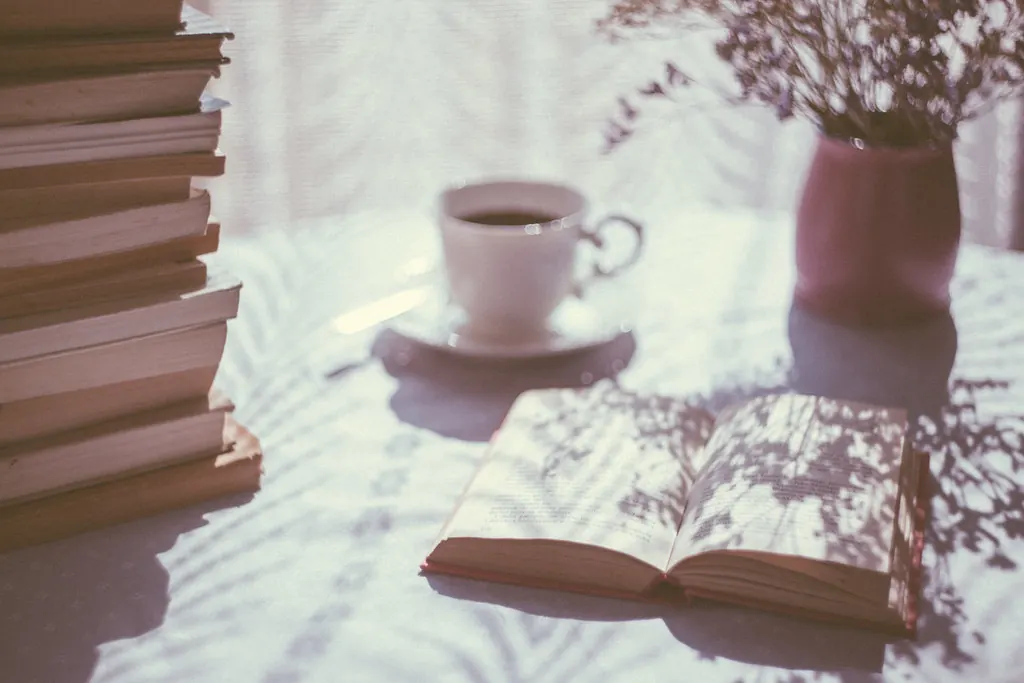 Open book and a cup of coffee on a table in soft morning light