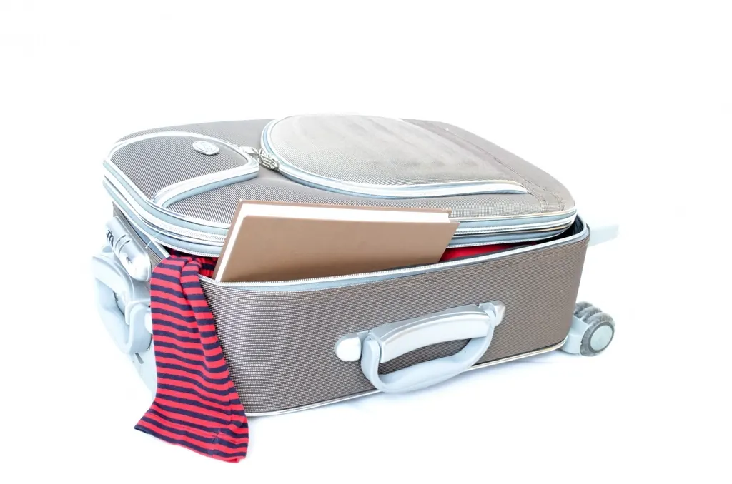 Carry-on suitcase packed with folded clothes and a notebook tucked inside