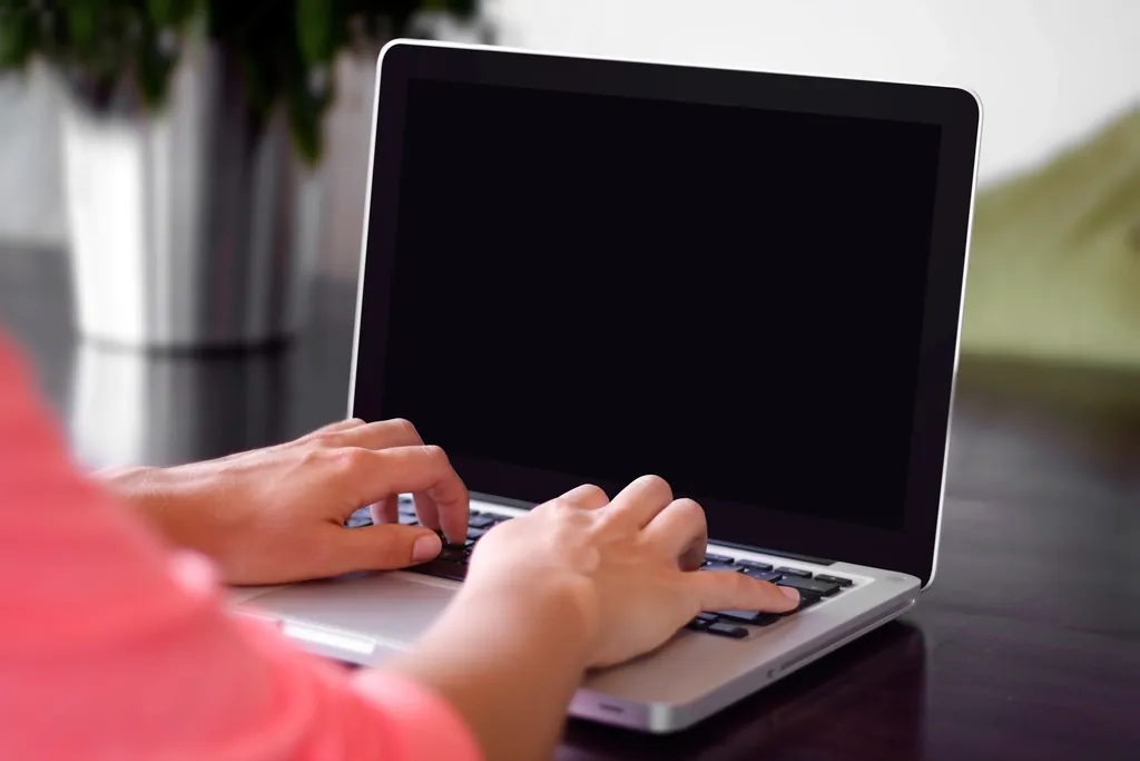 A person typing on a laptop at a desk
