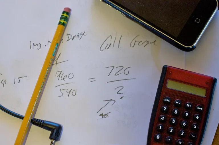 Handwritten calculations on paper beside a calculator