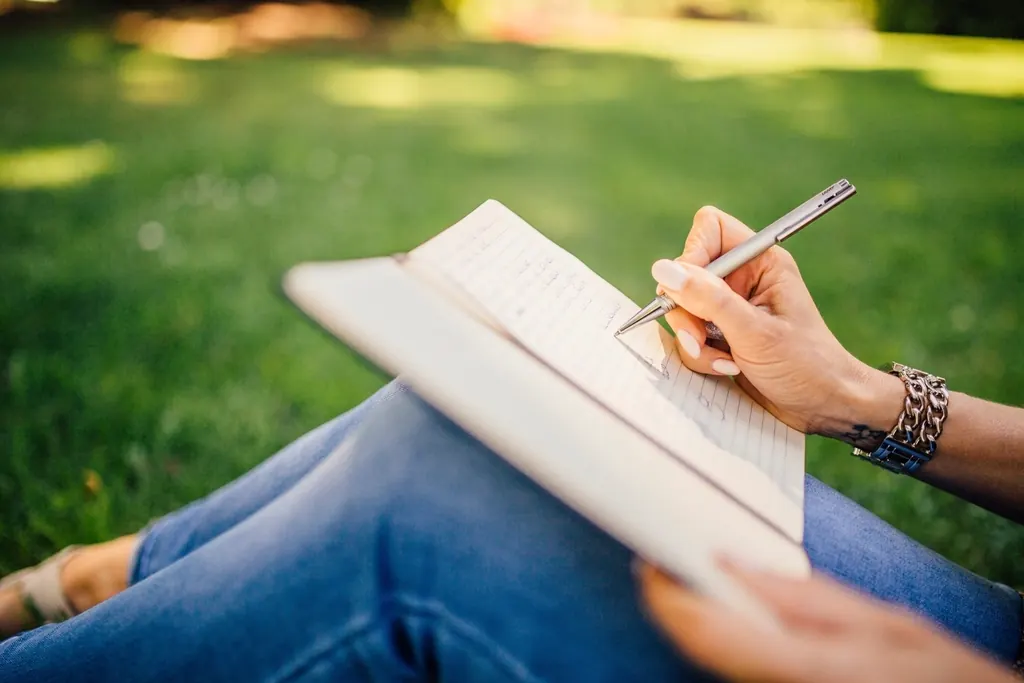 Hand writing notes in a paper journal outdoors